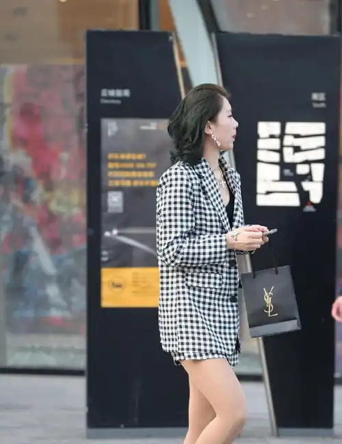 街拍美女黑色风衣披在肩上,非常个性,而且笑起来很迷人