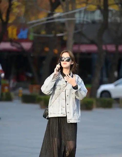 街拍美女黑色风衣披在肩上,非常个性,而且笑起来很迷人