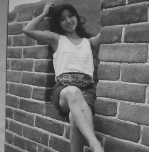 这张照片拍摄1983年夏,西安女大学生坐老城墙,面对镜头从容微笑