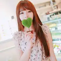 女生一只手拿着一片绿色的心型就放在嘴的位置的情侣头像